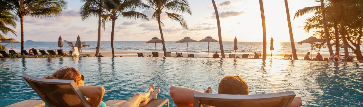 Couple relaxing on sun loungers by pool